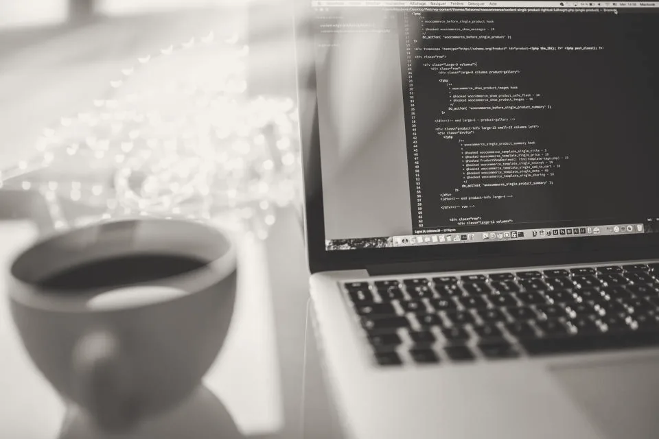 Laptop con código junto a una taza de café